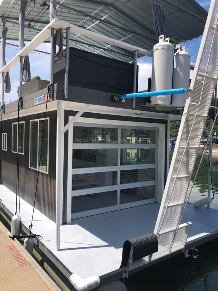Full-view aluminum and glass panel garage door installed on a two-story houseboat