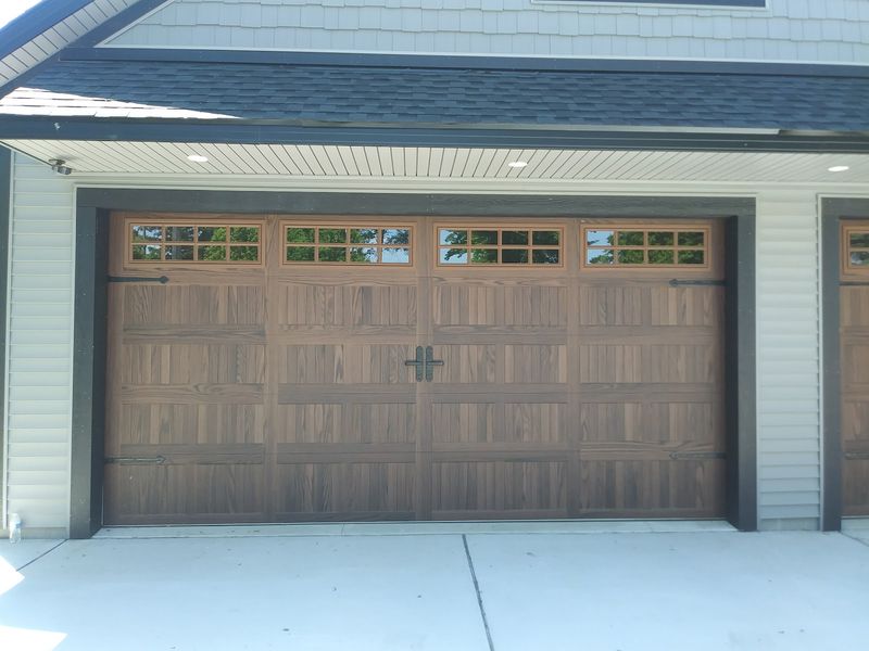 Wood-look two-car garage door with a row of windows and decorative center handle